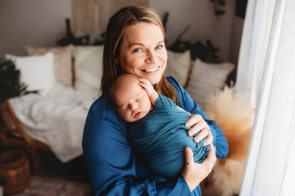 New mother embraces her infant during Newborn Photoshoot in Charleston, SC while receiving Breastfeeding Support in Charleston. 