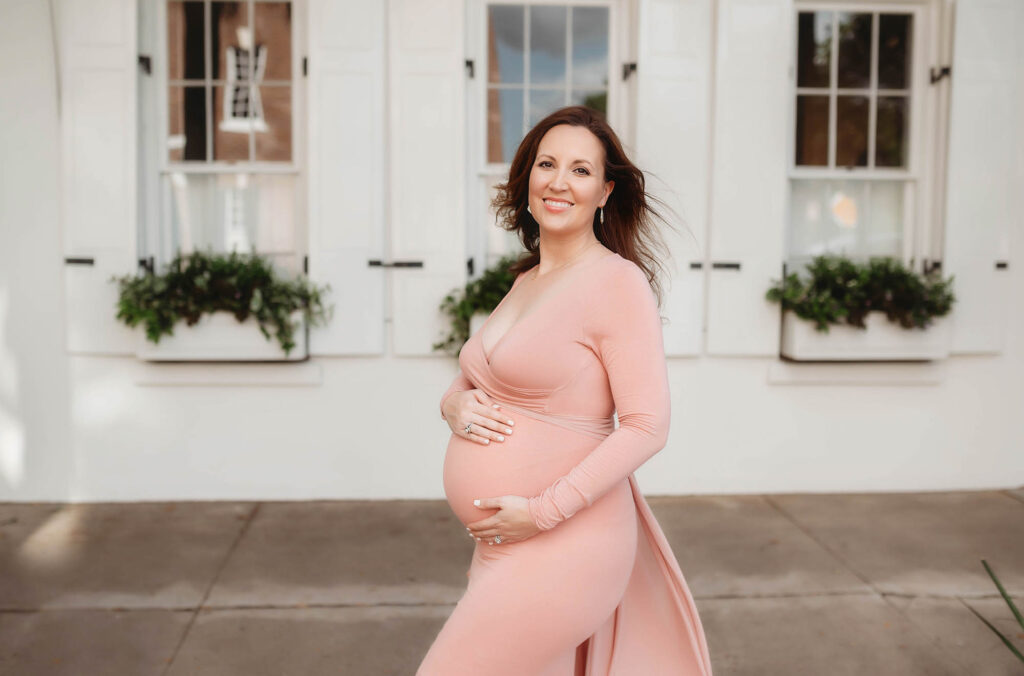 Pregnant mother embraces her baby bump during Maternity Photos on Rainbow Row in downtown Charleston, South Carolina.