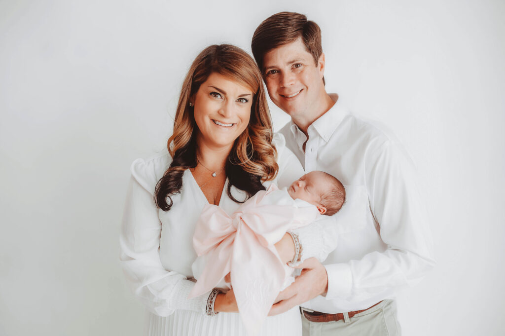 Parents embrace their infant during Newborn Portrait Photoshoot at Holy City Babies Portrait Studio in Charleston, SC.
