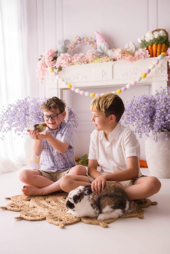 Siblings hold a baby chic and a live bunny during Easter Mini Session at Holy City Babies Portrait Studio in Charleston, SC. 