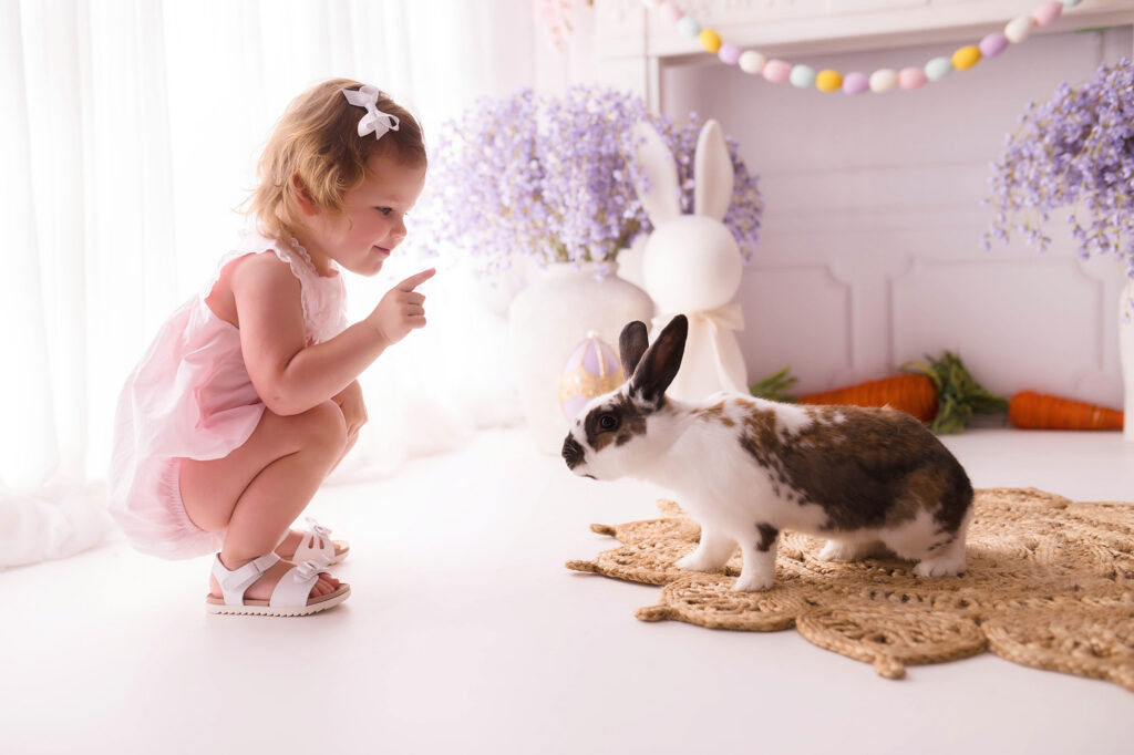 Toddler interacts with a live bunny  during Easter Mini Session at Holy City Babies Portrait Studio in Charleston, SC. 