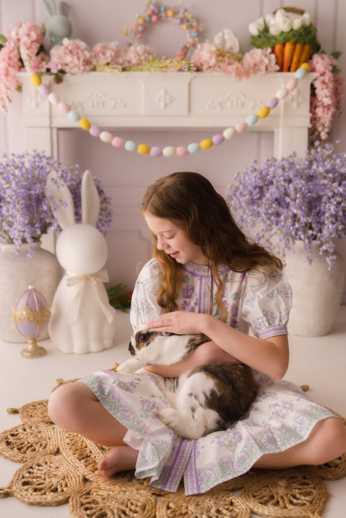 Young girl pets a live bunny during Easter Mini Session at Holy City Babies Portrait Studio in Charleston, SC. 