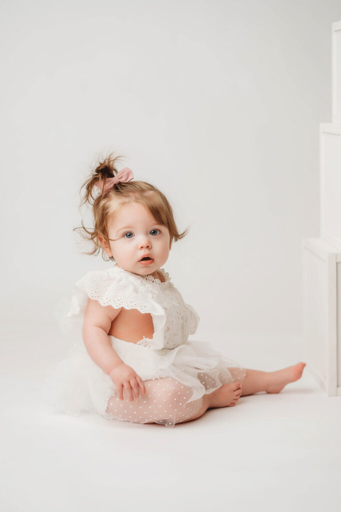 Charleston Milestone Photographer - baby peers at the camera during a studio Milestone Portrait Session at Holy City Babies Portrait Studio in Charleston, SC. 