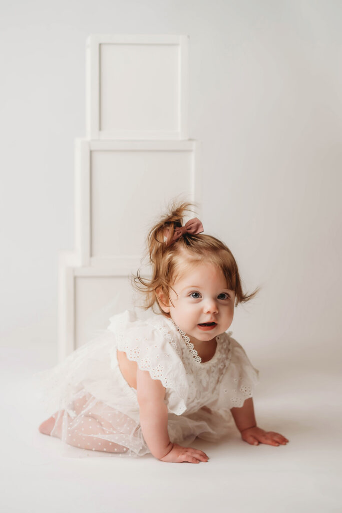 Charleston Milestone Photographer - baby peers at the camera during a studio Milestone Portrait Session at Holy City Babies Portrait Studio in Charleston, SC.