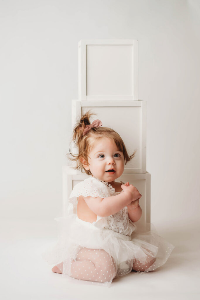 Charleston Milestone Photographer - baby peers at the camera during a studio Milestone Portrait Session at Holy City Babies Portrait Studio in Charleston, SC. 