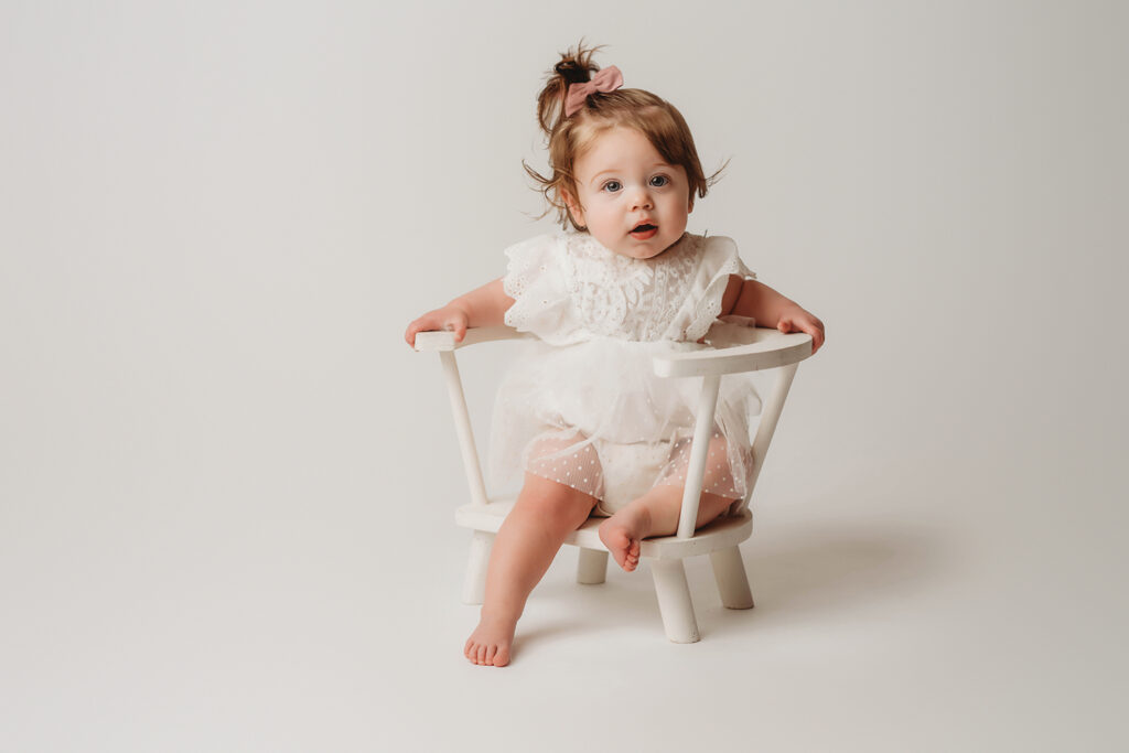 Charleston Cake Smash Photography - baby peers at the camera during a studio Milestone Portrait Session at Holy City Babies Portrait Studio in Charleston, SC. 