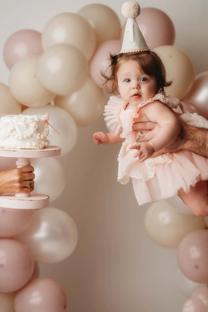 Charleston Cake Smash Photography - baby peers at the camera during a studio Milestone Portrait Session at Holy City Babies Portrait Studio in Charleston, SC. 