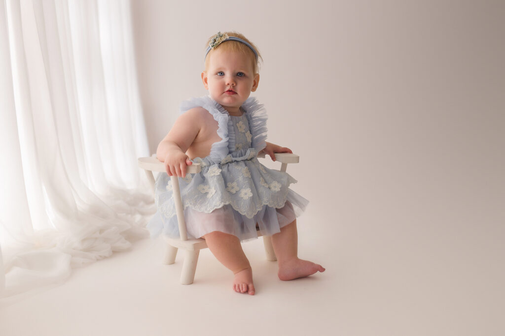 Luxury First Birthday Photography in Charleston - Baby peers at the camera during their First Birthday, Milestone, Cake Smash Photoshoot at Holy City Babies Portrait Studio in Charleston, SC.