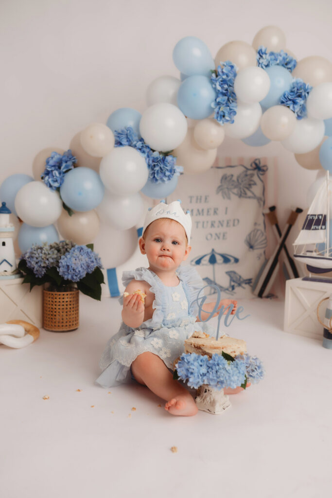 Baby peers at the camera during their First Birthday, Milestone, Cake Smash Photoshoot at Holy City Babies Portrait Studio in Charleston, SC.