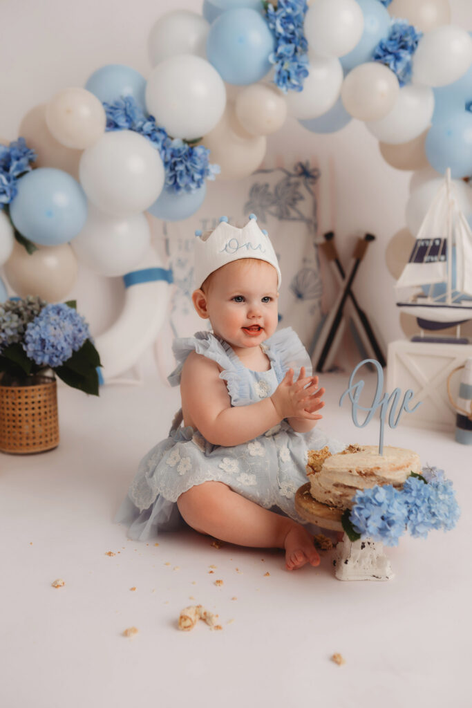 Luxury First Birthday Photography in Charleston - Baby peers at the camera during their First Birthday, Milestone, Cake Smash Photoshoot at Holy City Babies Portrait Studio in Charleston, SC.