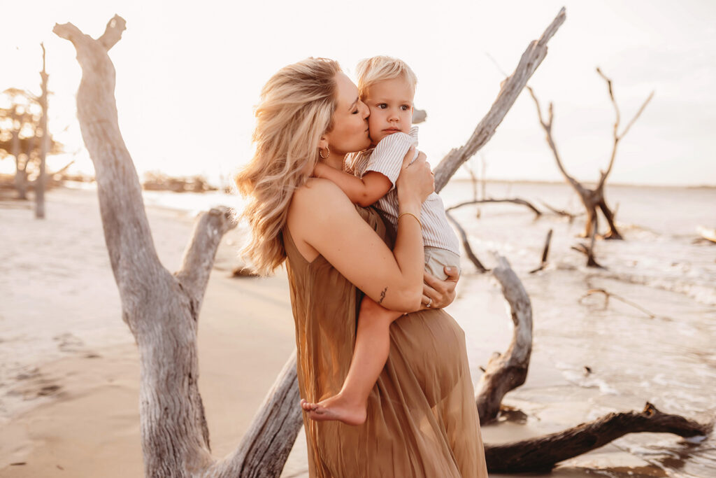 Pregnant mother kisses her toddler during Maternity Portraits at Folly Beach in Charleston, SC.