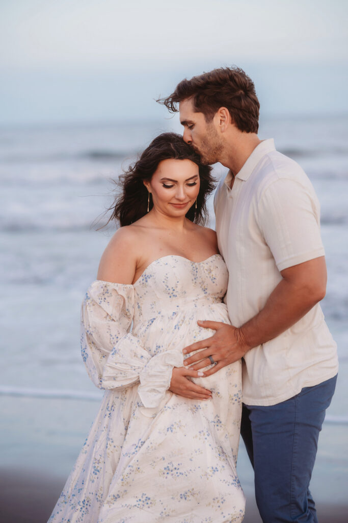 Expectant embrace on Folly Beach during their Maternity Portrait Session on Folly Beach after discovering The Ultimate Charleston Babymoon Planning Guide.