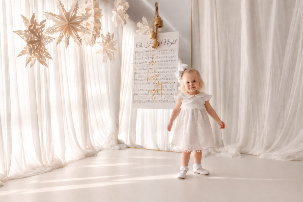 Toddler dances around the festive set design during Holiday Mini Sessions in Charleston at Holy City Babies Portrait Studio in the Avondale neighborhood of Charleston.